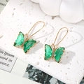 Exquisite golden butterfly earrings with green crystals on white stone surface - Pale Green