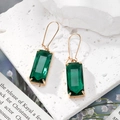Elegant gold earrings with rectangle emerald green crystal drops on white stone background - Green