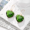 Detalle de pendientes de cristal verde en forma de corazón con borde dorado en bandeja - Verde