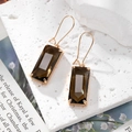 Détails macro des boucles d'oreilles pendantes en cristal ambre avec crochets dorés chic - Marron