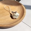 Dettaglio ravvicinato di un portachiavi a forma di coniglio bianco in un vassoio di legno - Maialino Bianco Floccato