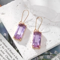 Detail of purple crystal rectangle earrings with golden hooks on white stone - Purple