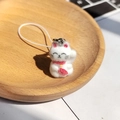 Detail van een witte gevlokte gelukskat hanger met een rode halsband en goud belletje - Bevlokte Gelukskat