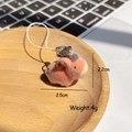 Macro shot of a pink and grey plush animal keychain with metal ring and white cord - Flocked Horse