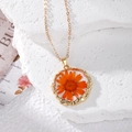 Macro detail of natural orange dried flower preserved in clear resin necklace pendant - Orange
