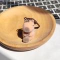 Nahaufnahme eines süßen orangefarbenen Kapybara-Schlüsselanhängers auf einem Holztablett - Holzfisch Capybara