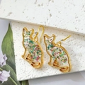 Detailed close-up of cat-shaped gold earrings with colorful dried flowers in resin - Floral Sitting Cat