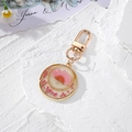 Detailed macro view of gold-rimmed resin keychain with pink dried flowers and clasp - Round Pink Daisy Floral