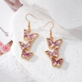 Macro view of triple butterfly drop earrings with purple dried flowers in gold frames - Purple Butterfly