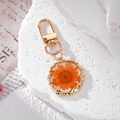 Detailansicht des Harzanhängers mit echter oranger Gänseblümchenblüte und Goldrand - Orange Gänseblümchen
