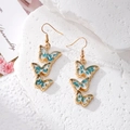 Macro detail of triple butterfly drop earrings with blue dried flowers in gold resin - Blue Butterfly