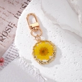 Close-up of yellow dried flower daisy pendant in resin with golden wavy metal frame - Yellow Daisy