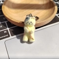 Nahaufnahme eines beflockten Harz-Katzen-Schlüsselanhängers auf einem Holztablett vor Tastatur - Kätzchen mit Harpune