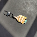 Detailed view of fish-shaped plush keychain with yellow stripes and metal lobster clasp - Orange White Fish