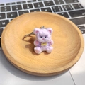 Dettaglio di un portachiavi orsetto di peluche viola con fiocco giallo e chiusura in metallo - Orso Abbraccio Viola