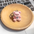 Simpatico portachiavi a forma di orsetto di peluche rosa con papillon blu su vassoio in legno - Orso Abbraccio Rosa