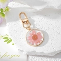 Detailed macro view of handmade pink daisy resin keychain with gold leaf on textured rock - Pink Daisy