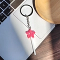 Detailed view of pink star lollipop keychain with sequins on a laptop and wooden desk - Red Star Lollipop