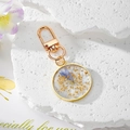 Dettaglio portachiavi rotondo in resina con fiori secchi blu e foglia d'oro lucida - Floreale Blu e Bianco