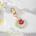Portachiavi fatto a mano in resina con fiori secchi rossi e foglia d'oro nel cerchio - Fiore Fucsia
