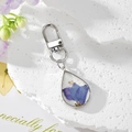 Dettaglio del portachiavi a goccia d'argento con fiori secchi blu e foglia d'oro vera - Floreale Viola