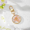 Detailed view of handmade clear resin keychain with pink dried flower and gold foil flakes - Pink Floral