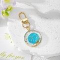 Détail d'un porte-clés rond en résine avec motif nébuleuse bleue et feuille d'or - Fleur Ronde Bleu Lac
