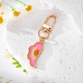 Détail d'un porte-clés doré avec marguerite séchée dans de la résine rose pastel - Rose Rouge Marguerite Aile