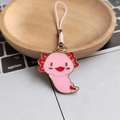 Pink axolotl alloy keychain with woven strap on wooden tray near laptop keyboard - Raised Hands