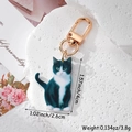Macro shot of cute tuxedo cat acrylic keychain with dimensions 4cm height and gold clasp - Black and White Cat
