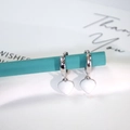 Close-up of silver-tone hoop earrings featuring white enamel heart charms on a stand - Heart Pendant / White Heart