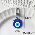 Blue resin Evil Eye keychain with silver lobster clasp on white tray, 6.4cm x 3cm - Round Shape