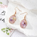 Detail of handmade resin earrings with dried flowers and copper wire wrap detailing - Pink Purple Style