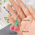 Detail view of a pink flocked cherry charm with green leaves and silver clasp, 9.8cm long - Pink Cherry (6MR50)