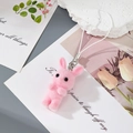 Close-up of pink flocked rabbit keychain with white strap on a decorative background - Pink Rabbit