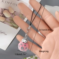 Detail shot of a cute pink flocked ladybug charm with size labels and hand scale - Pink Ladybug (10MR10)