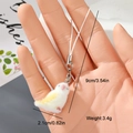 Detail view of mini plush bird charm showing 9cm length with silver lobster clasp and strap - White and Yellow Fledgling (17MR09)