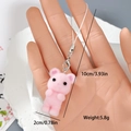 Close-up of pink flocked bear charm with silver lobster clasp held in hand - Pink Mouse