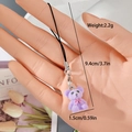 Detail of purple flocked bear keychain with lobster clasp held by a model hand - MR70 Purple Bear