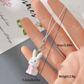 Handheld shot of a mini white flocked rabbit charm with pink flowers for bags and phones - Rabbit with Pink Flower (9MR18)