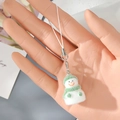 Close-up of adorable flocked snowman keychain with green hat and scarf on a cozy background - White Green Snowman (10MR54)