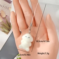 Detail showing plush white teddy dog charm held by hand for size and scale reference - Hugging Dog (MR71)