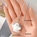 Detail view of a white flocked puppy charm with silver lobster clasp and woven cord lanyard - Sit Puppy (MR14)