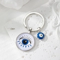 Macro view of blue Evil Eye glass charm keychain with silver metal pendant details - Blue Triangle Eye