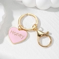 Dettaglio portachiavi a cuore rosa con scritta Honey e chiusura a moschettone dorata - Cuore Rosa Honey