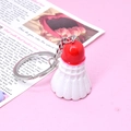 Close-up of red and white shuttlecock keychain with detailed texture on pink background - Red