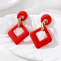 Gros plan de boucles d'oreilles losanges rouges mats sur un plateau décoratif blanc - Boucles d'Oreilles Carrées / Rouge