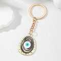 Irregular oval Evil Eye keychain with marble texture and golden polished metal rim - Black Oval Eye