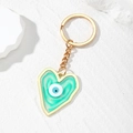 Detailed macro view of heart-shaped evil eye keychain with gold chain and marble resin texture - Green Heart