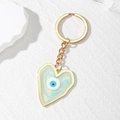 Macro detail of heart-shaped evil eye keychain with blue marble resin and gold frame - Light Blue Heart